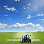 Farming tractor plowing and spraying on corn field